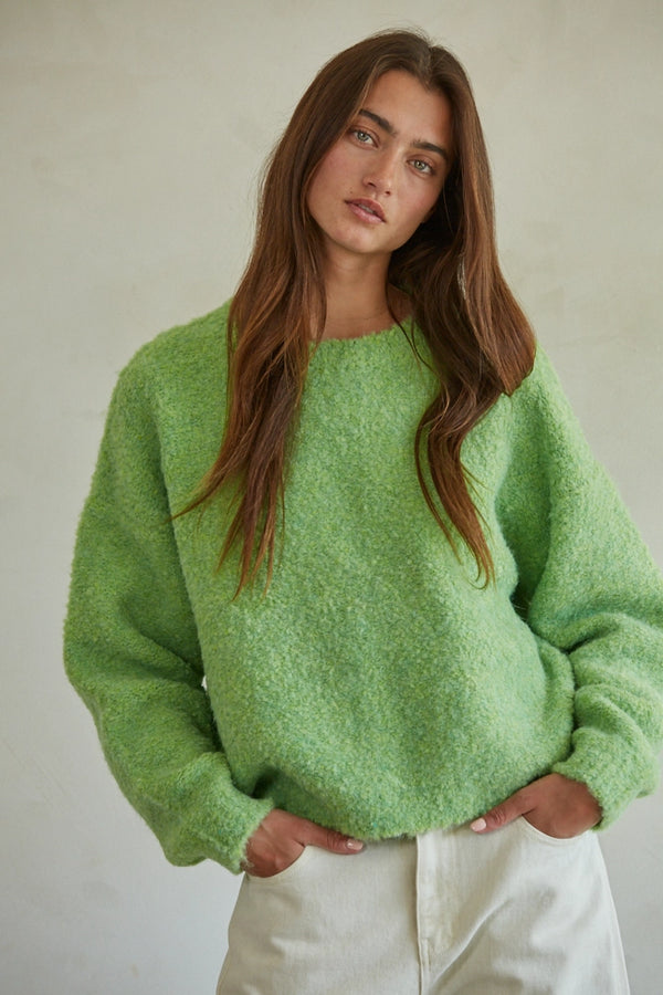 Model wearing lime green pullover sweater with round neck and relaxed fit, styled with ivory pants.