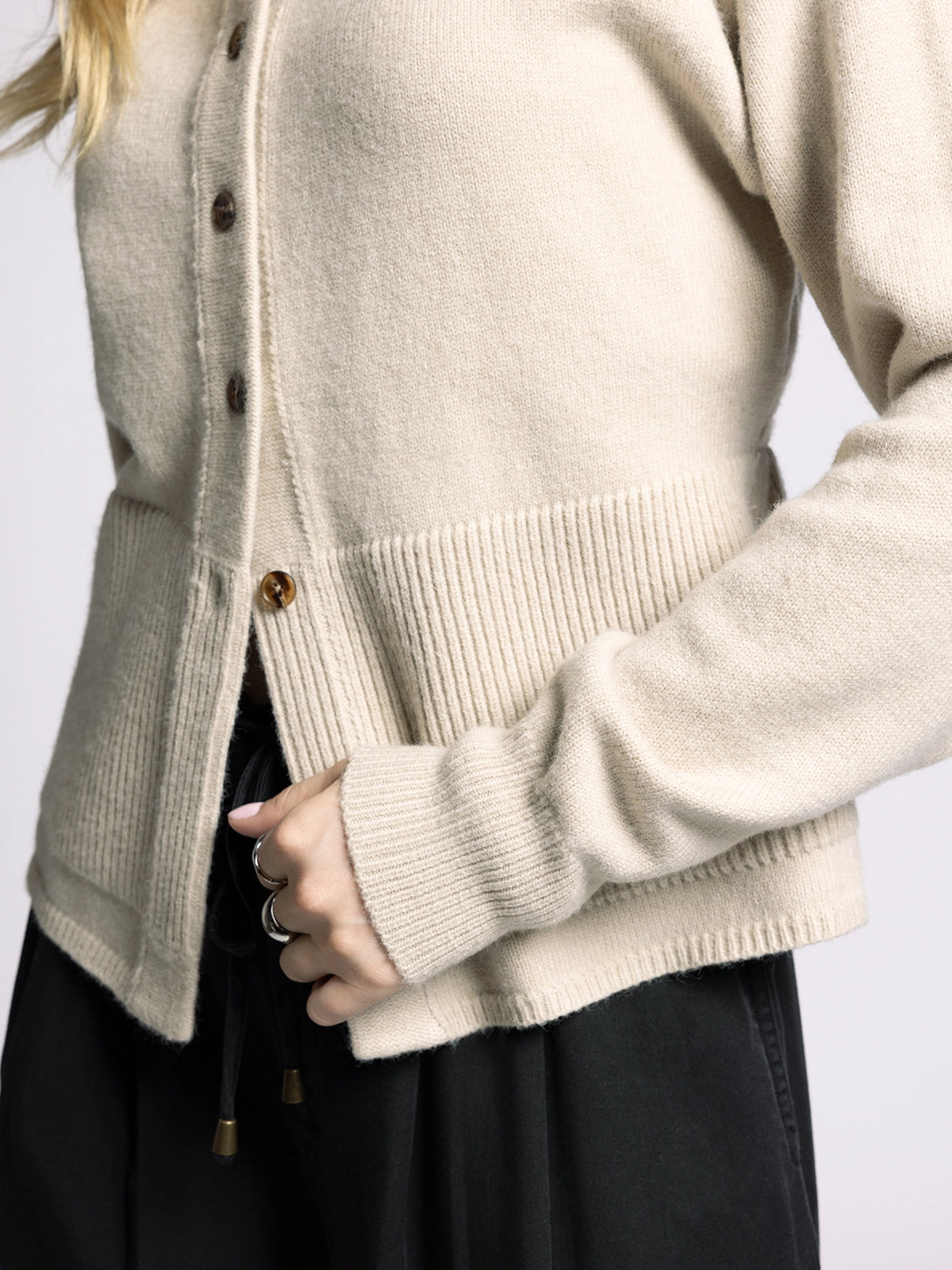 Close-up detail of Michelle Cardigan by The Weekend LA showing ribbed hem, button closure, and peplum knit texture.