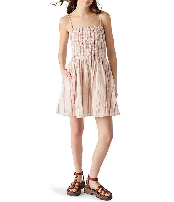 Woman wearing a pink smocked dress on a white background