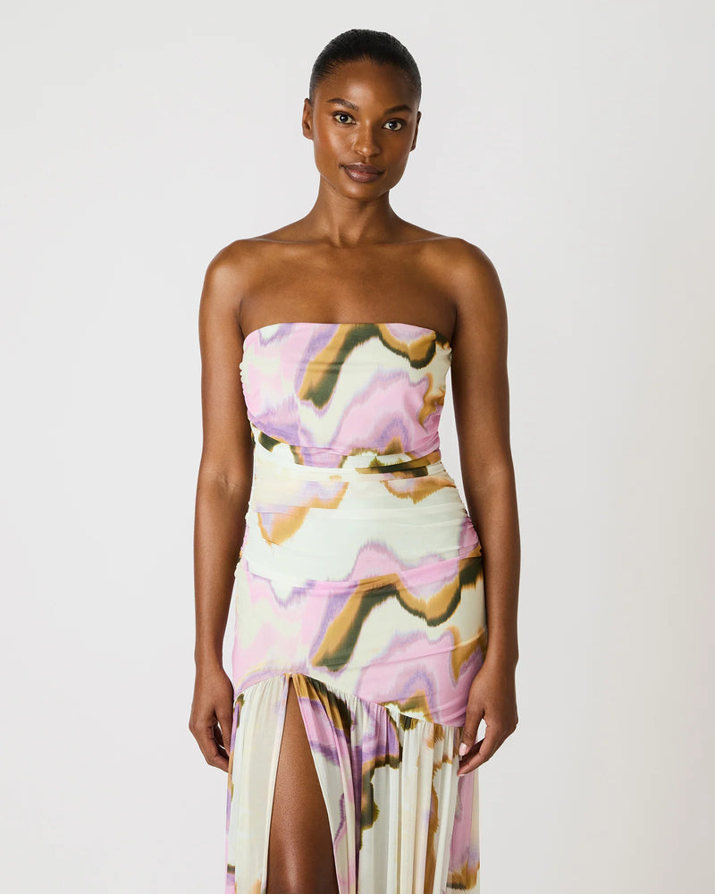 Woman wearing a strapless dress with a colorful abstract pattern on a white background