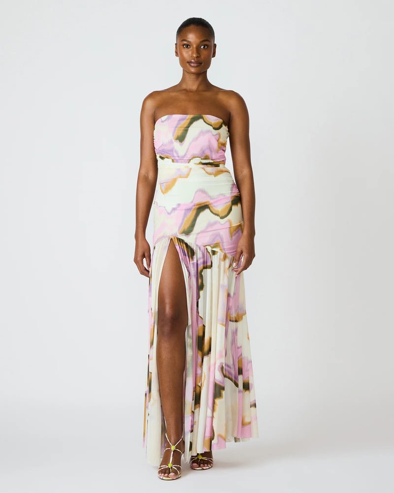 Woman wearing a strapless, floral-patterned gown with a slit on a white background