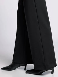 Close-up of black wide-leg pant hem showing structured finish and sleek fabric.