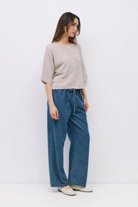 Side view of minimalist beige cardigan, half sleeves and button detail.