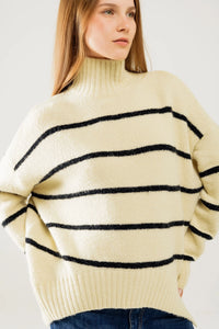 Side view of cozy oversized striped sweater with mock neck and side slits, styled with denim jeans.