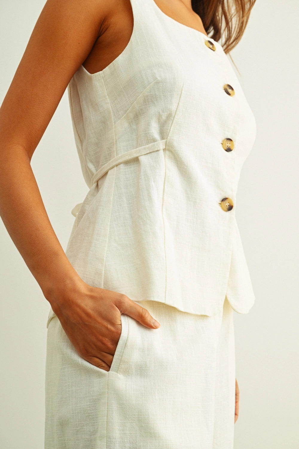 Close up of tortoise shell buttons on cream linen vest top for women