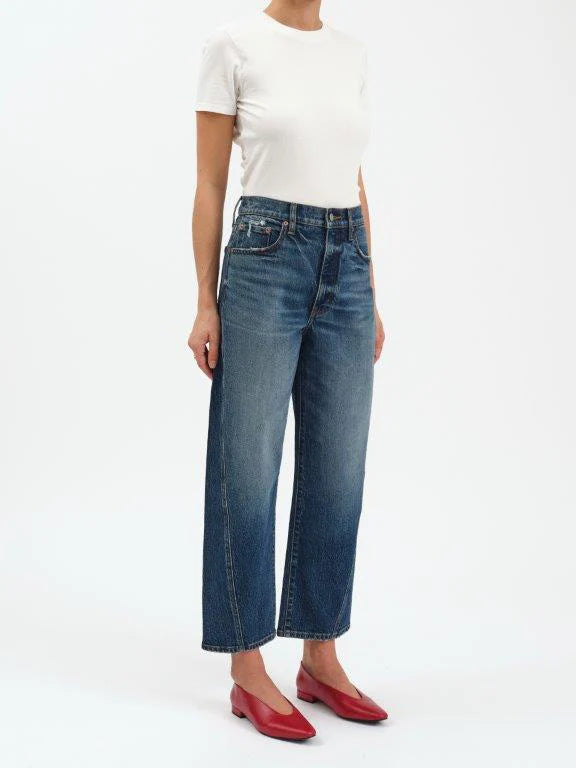 Person wearing blue jeans and a white top on a white background