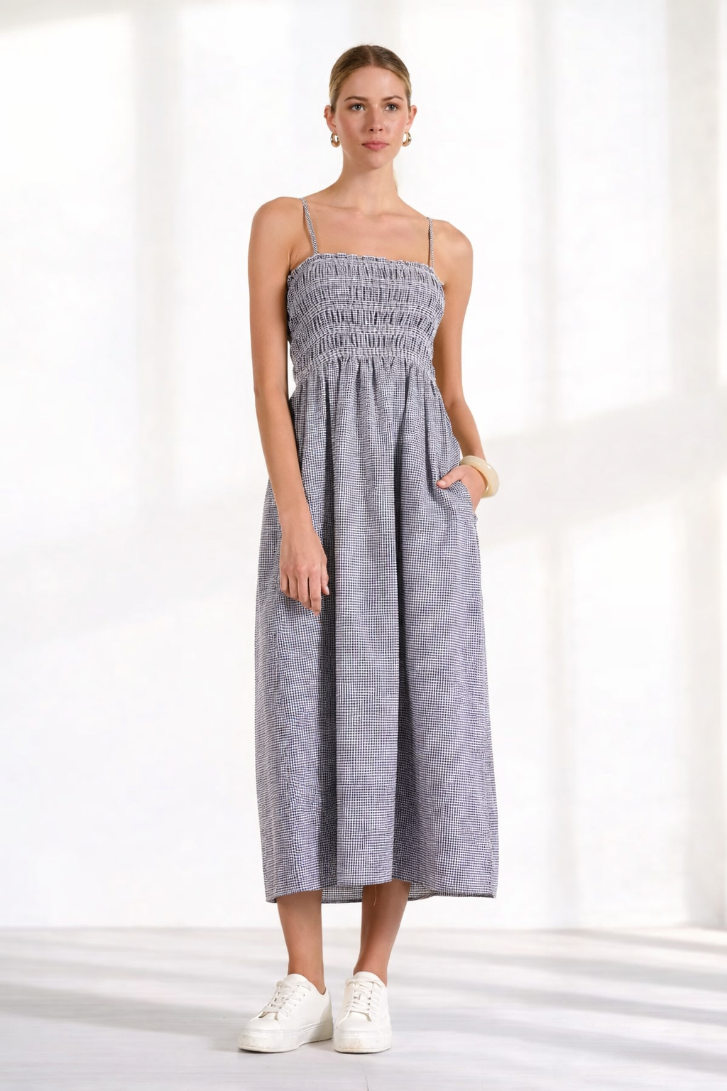 Women's gingham midi dress with smocked bodice and flowy skirt styled with white sneakers