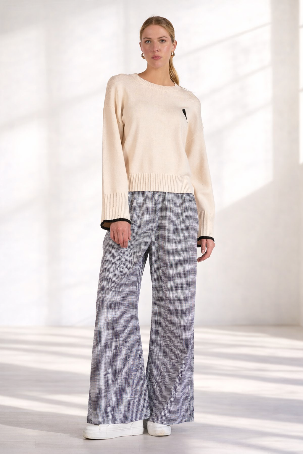 Women's black and white gingham wide leg pants styled with cream sweater and sneakers