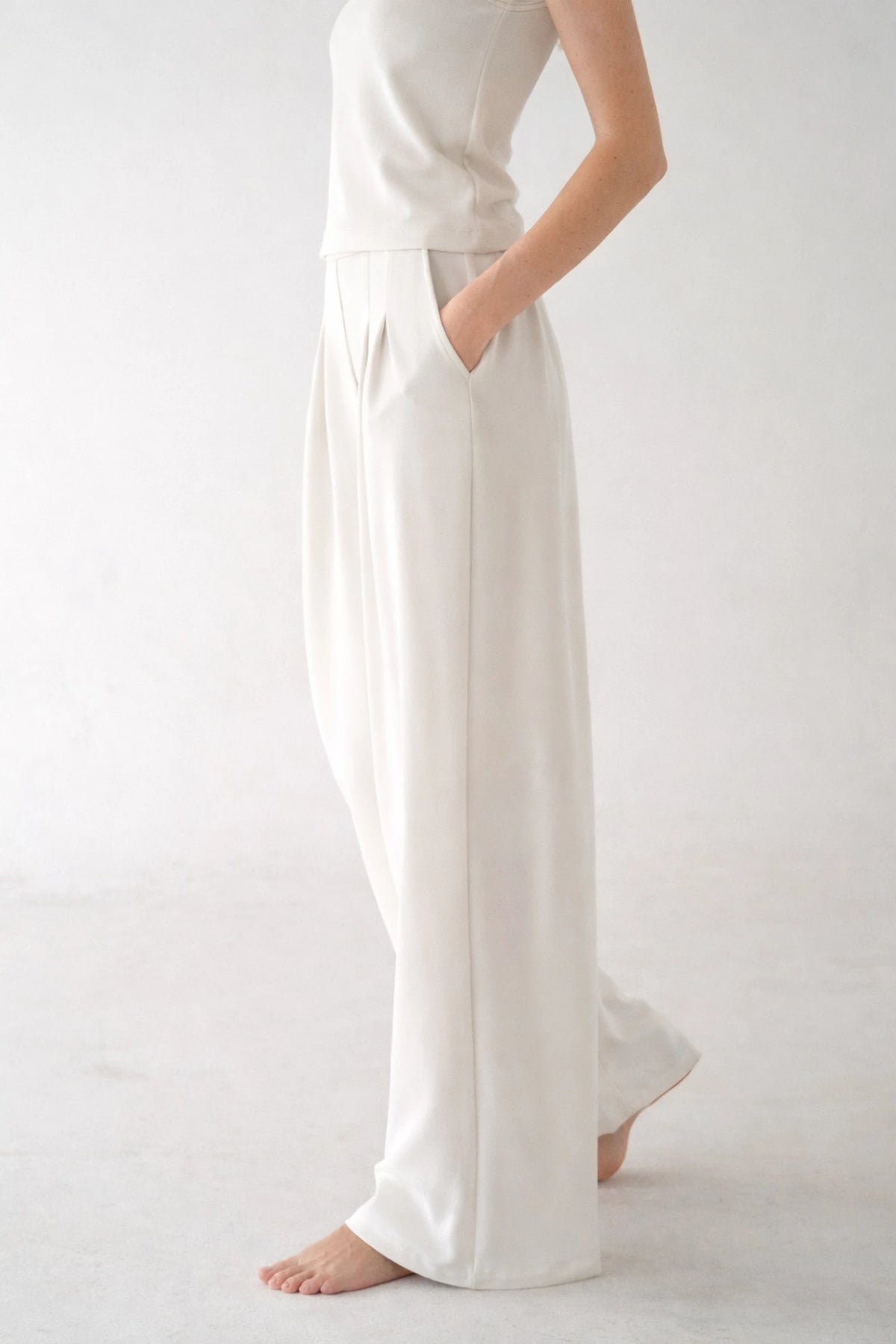 Side profile of elegant ivory wide-leg lounge pants, highlighting the fluid drape of the fabric and functional side pockets.