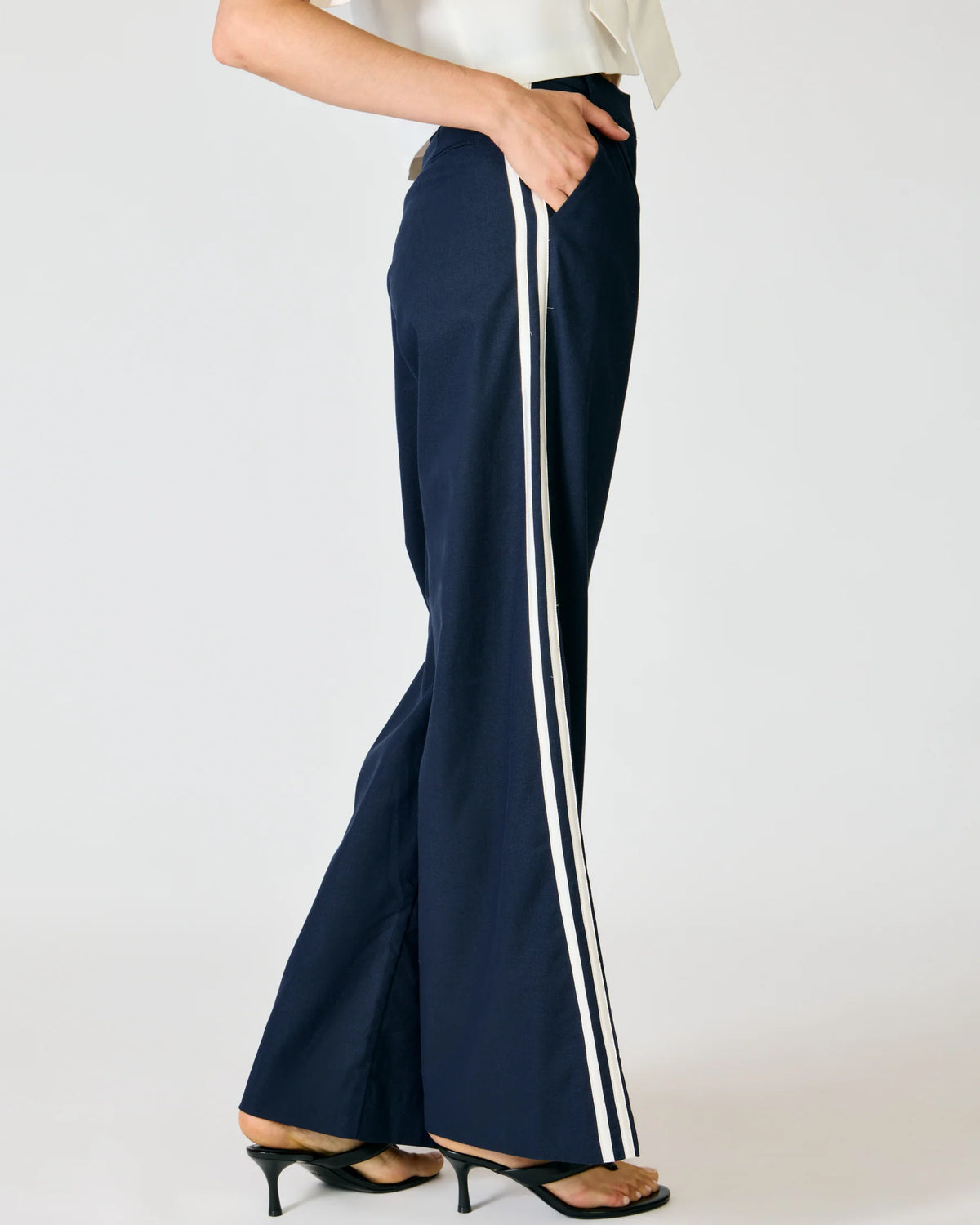 Close-up detail of the Line and Dot Anchor Pants, highlighting the double white contrast binding stripe running down the side seam of the navy trousers.