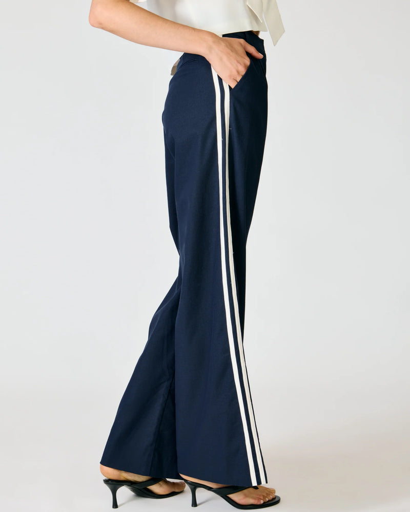 Close-up detail of the Line and Dot Anchor Pants, highlighting the double white contrast binding stripe running down the side seam of the navy trousers.