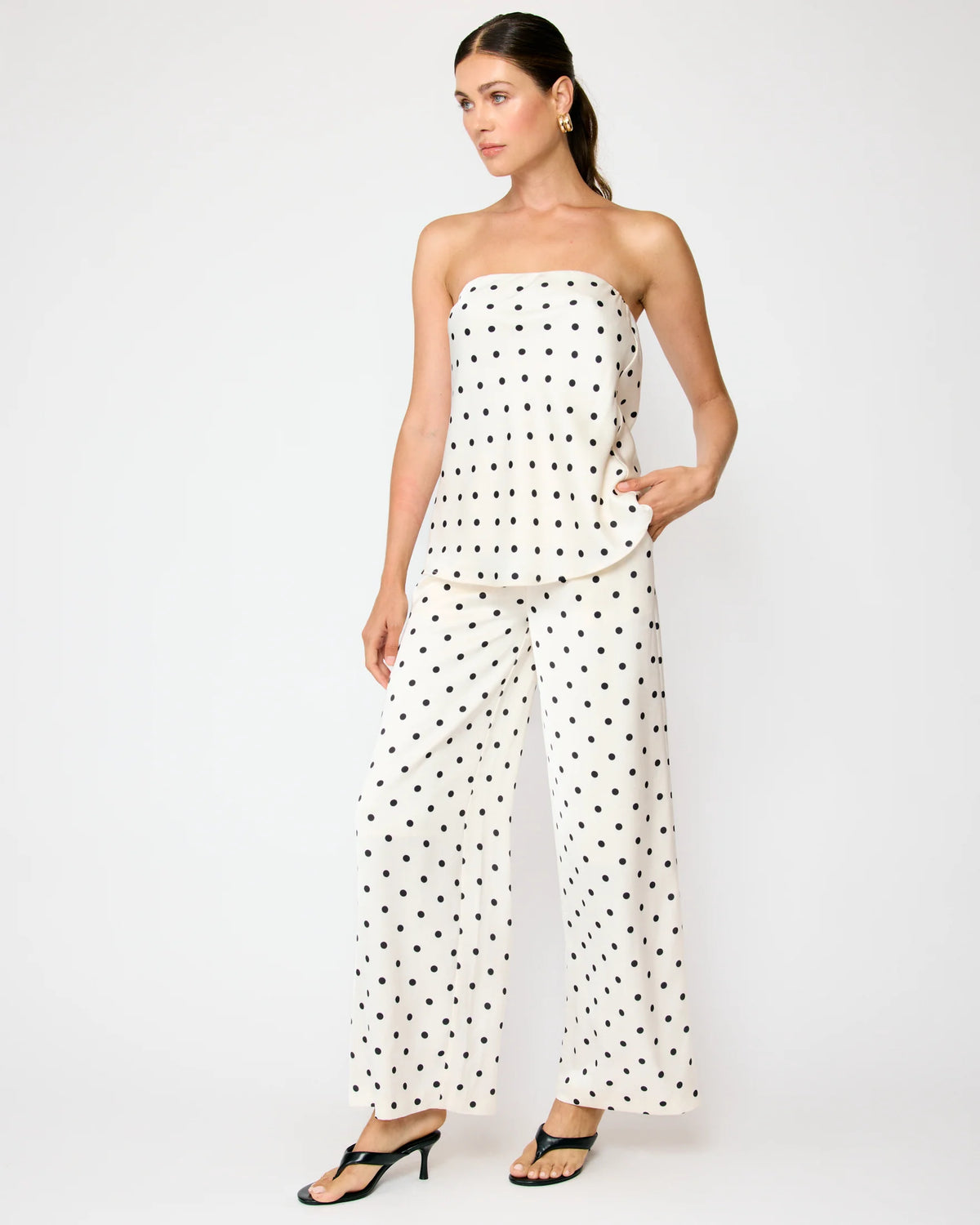 Woman wearing a strapless polka dot jumpsuit on a white background