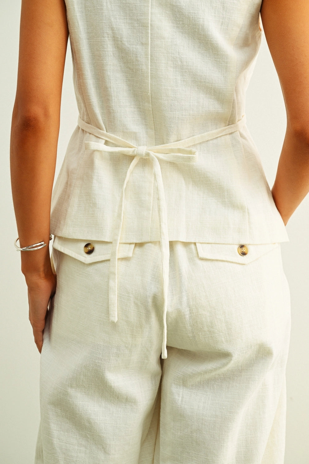 Back view of cream linen vest top with adjustable tie waist detail