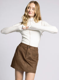 Model wearing the Marisol Mock Neck Top in cream with contrast seam detail and fitted silhouette.