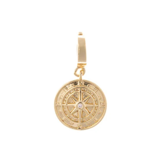 Close-up of the Michelle McDowell 18k gold plated compass symbol charm featuring a center crystal detail and clip-on clasp.