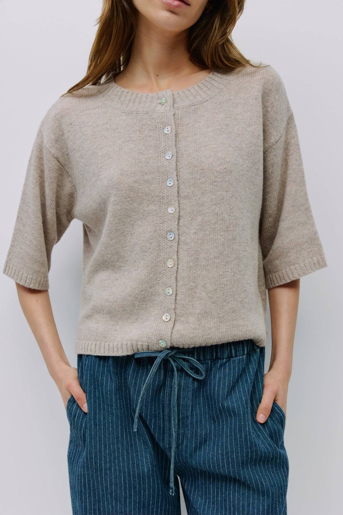 Front view of soft beige cardigan with pearl buttons and relaxed fit.