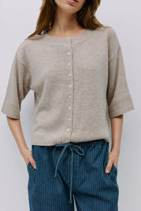Front view of soft beige cardigan with pearl buttons and relaxed fit.