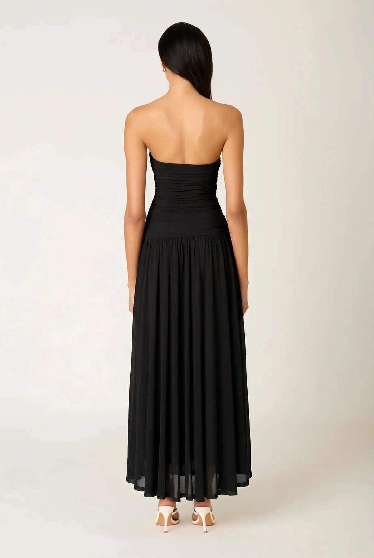 Back view of the NIA Beverly Maxi Dress, displaying the clean strapless back design, hidden side-zip closure area, and floor-sweeping pleated skirt.