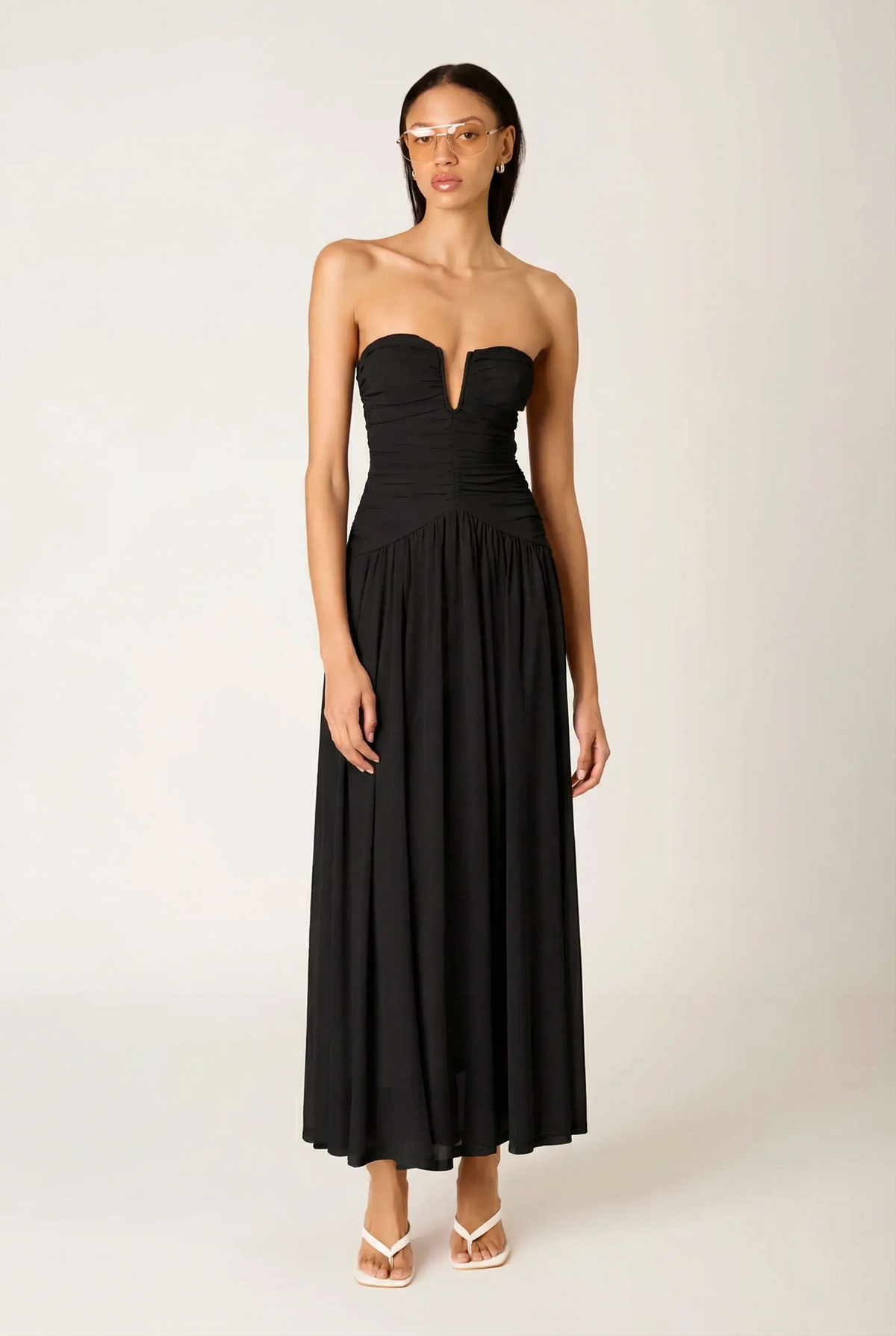 Model wearing the black NIA Beverly strapless maxi dress, highlighting the fit-and-flare silhouette and elegant drape of the chiffon fabric.