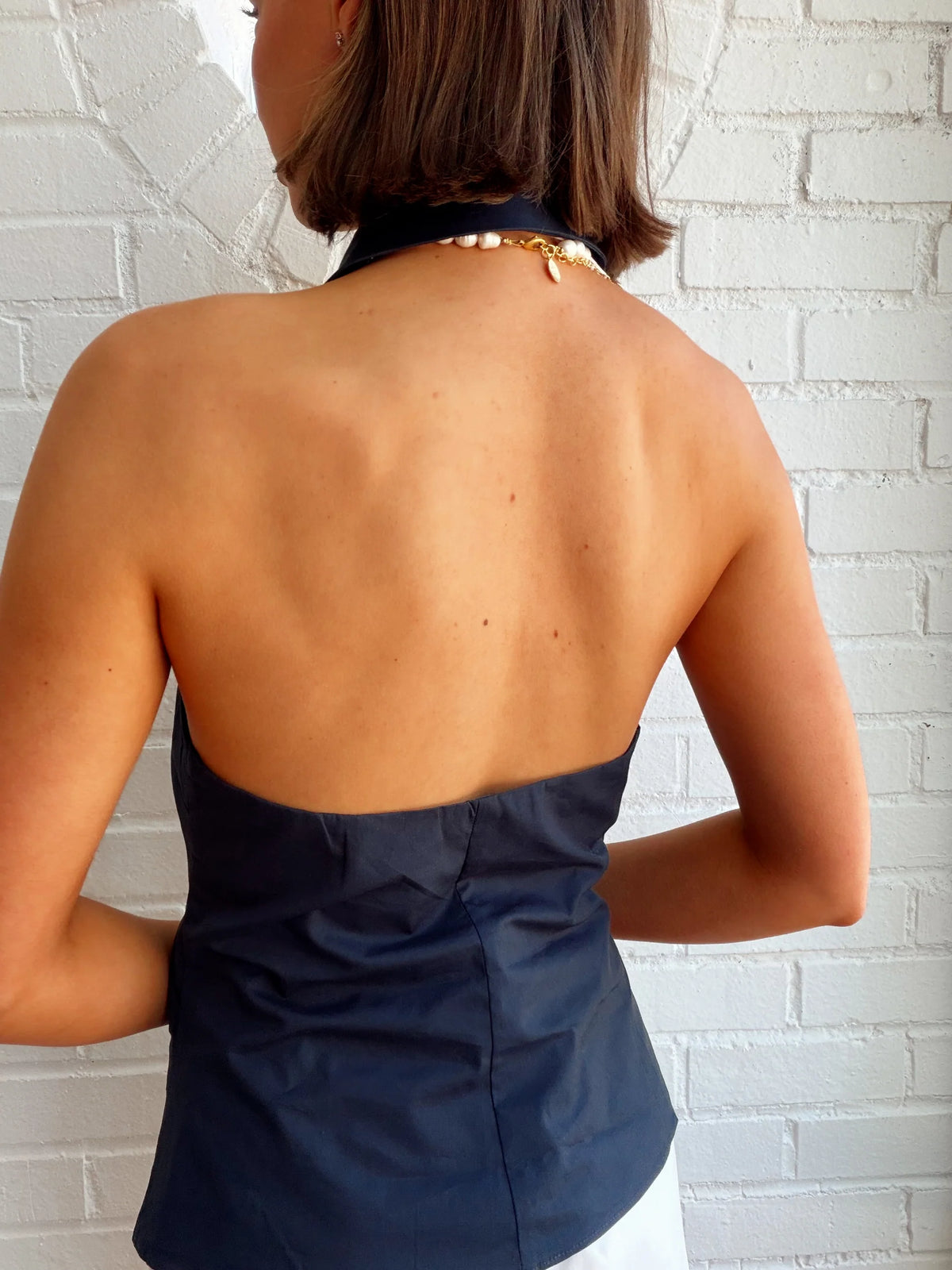 Back view of the NIA Valle navy halter top showing the adjustable neck strap and tailored fit.