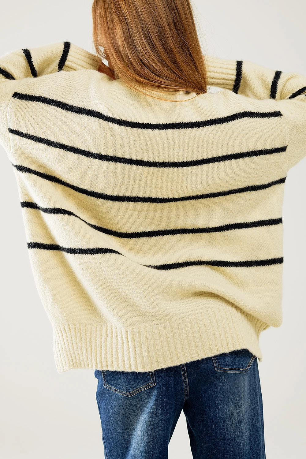 Back view of oversized striped sweater showing side slit and ribbed hem details.