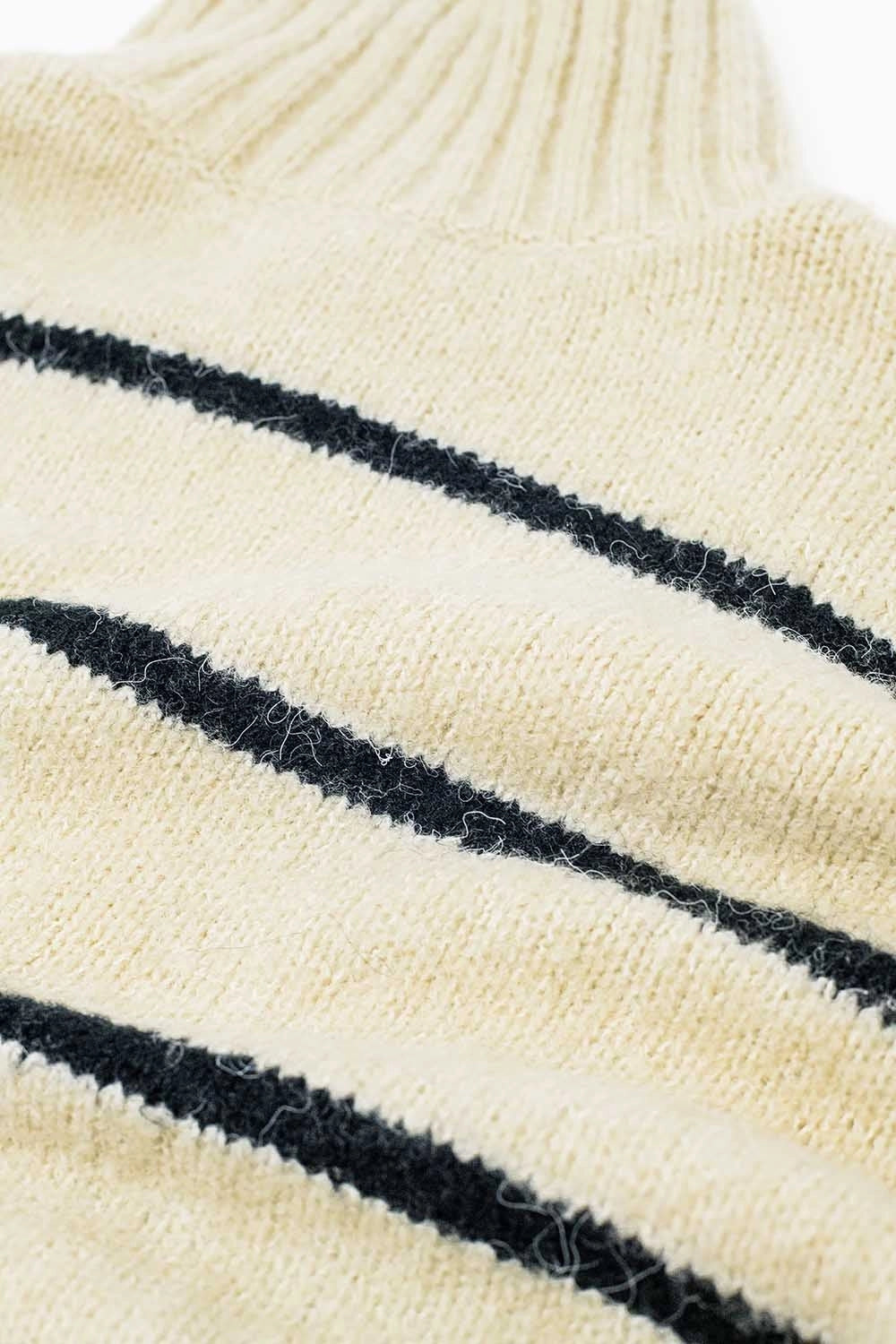 Close-up of soft knit texture and black stripe pattern on cream sweater.