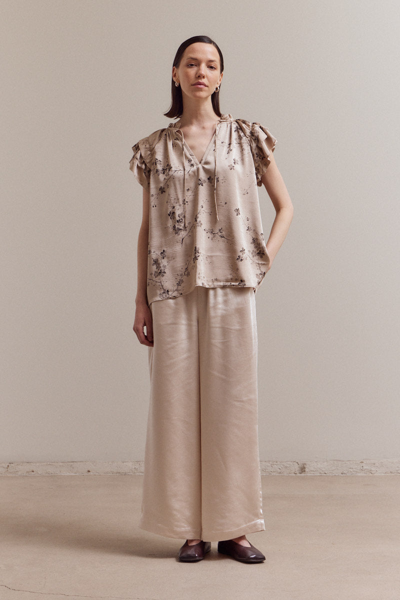 Full outfit look featuring Perry Ruffle Sleeve Blouse in beige satin floral print paired with wide-leg trousers — feminine boutique top.