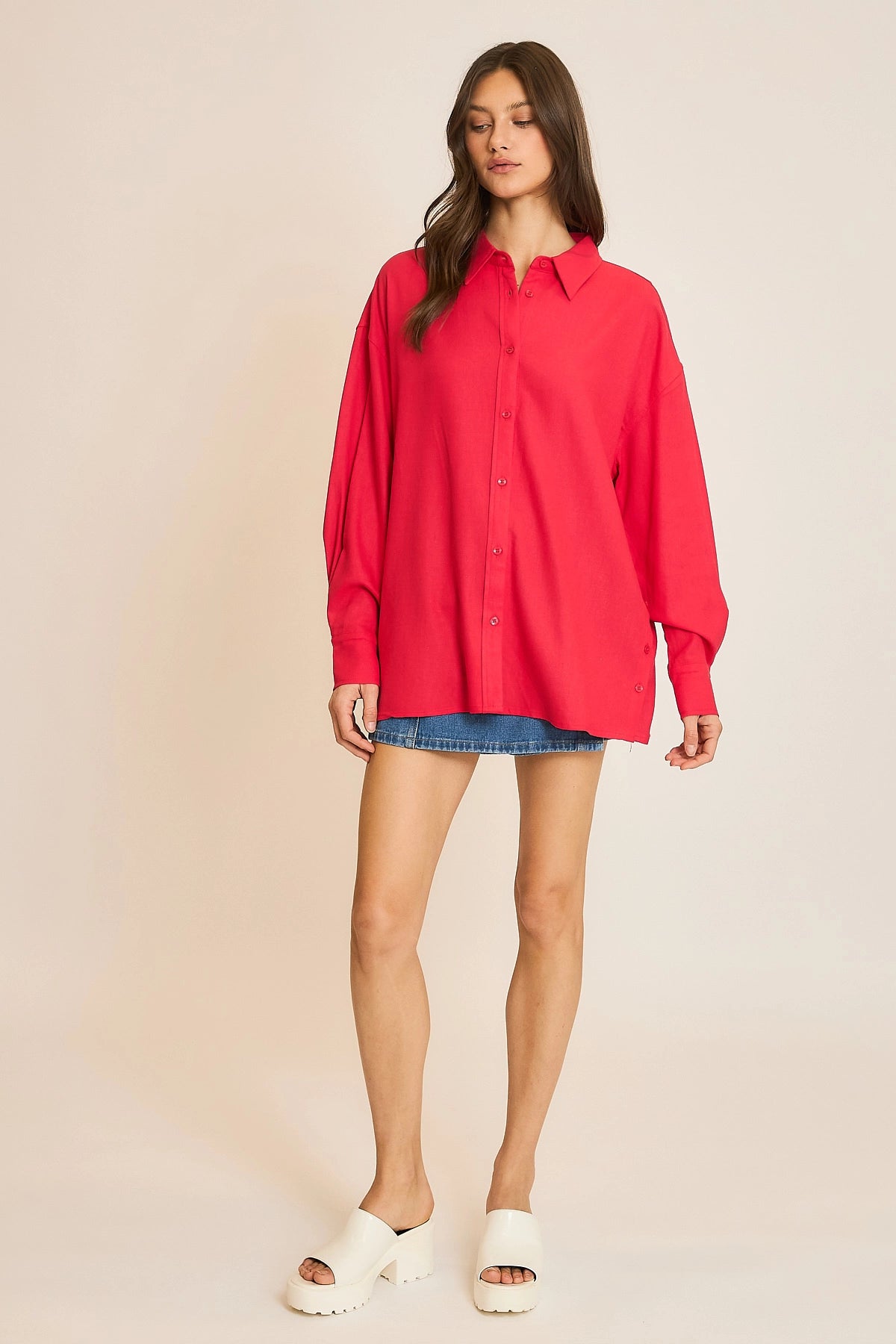 Woman wearing a red shirt and denim skirt on a beige background