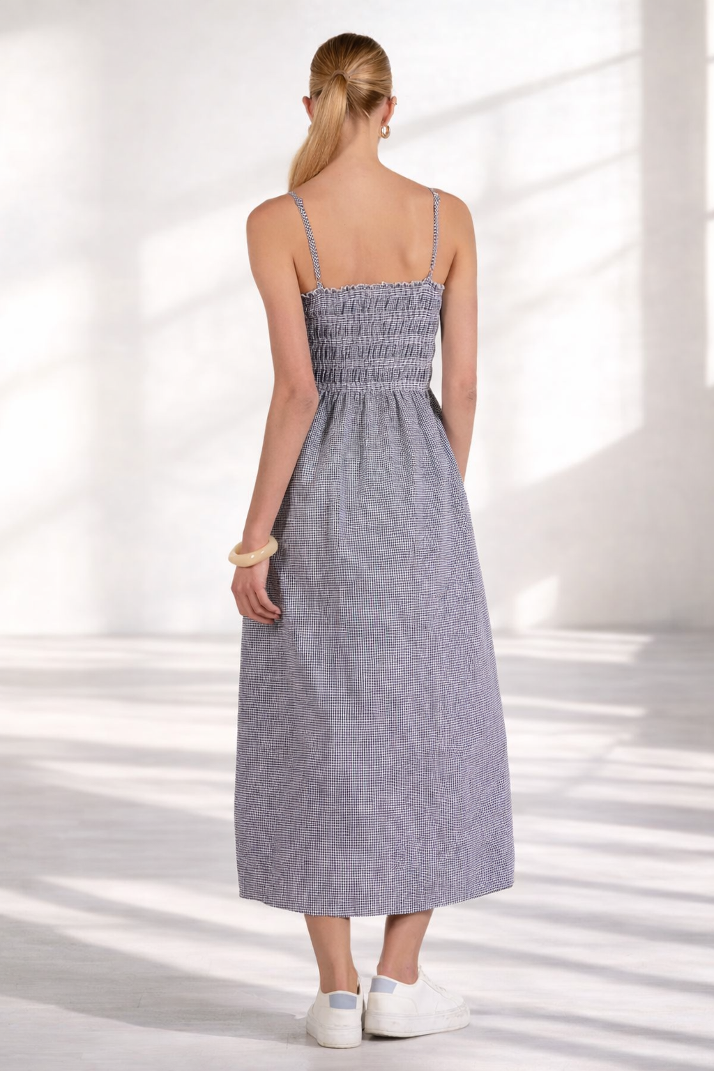 Back view of women's smocked gingham midi dress with adjustable straps and relaxed skirt