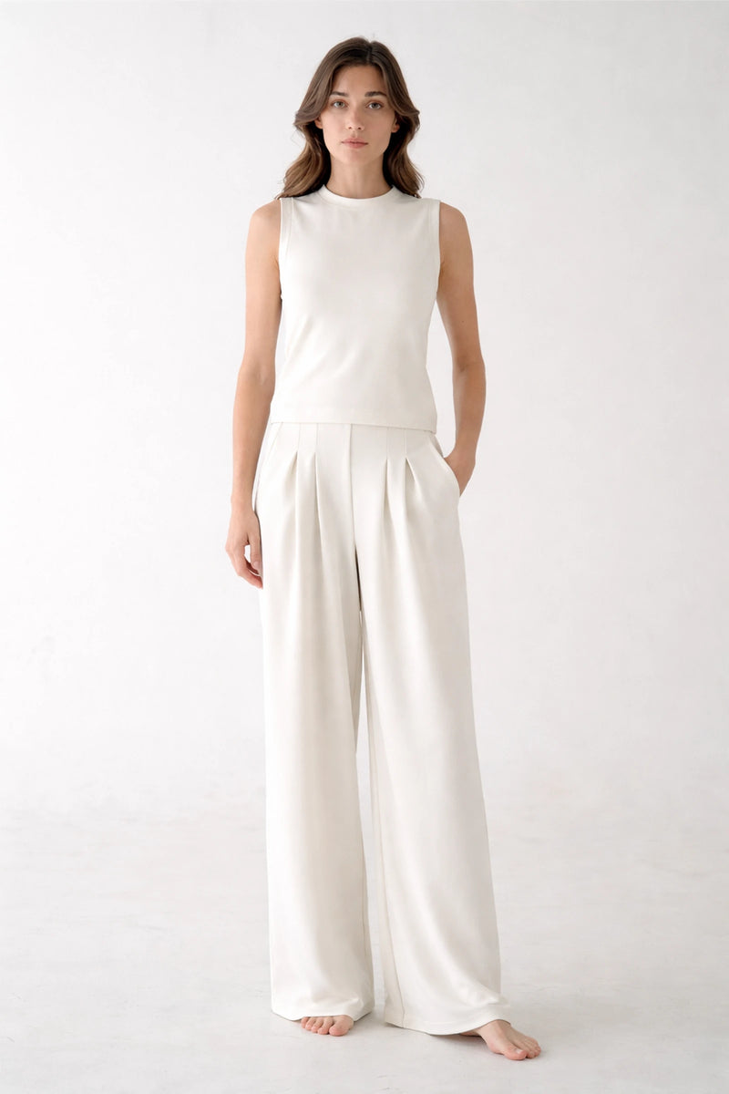 Front view of a woman wearing high-waisted white pleated wide-leg sweatpants, showing the tailored trouser look and relaxed fit.