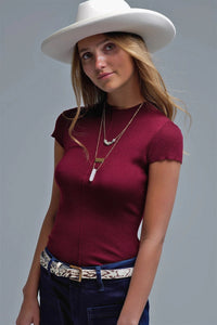 Model wearing wine ribbed knit cap sleeve top with mock neckline, styled with jeans.