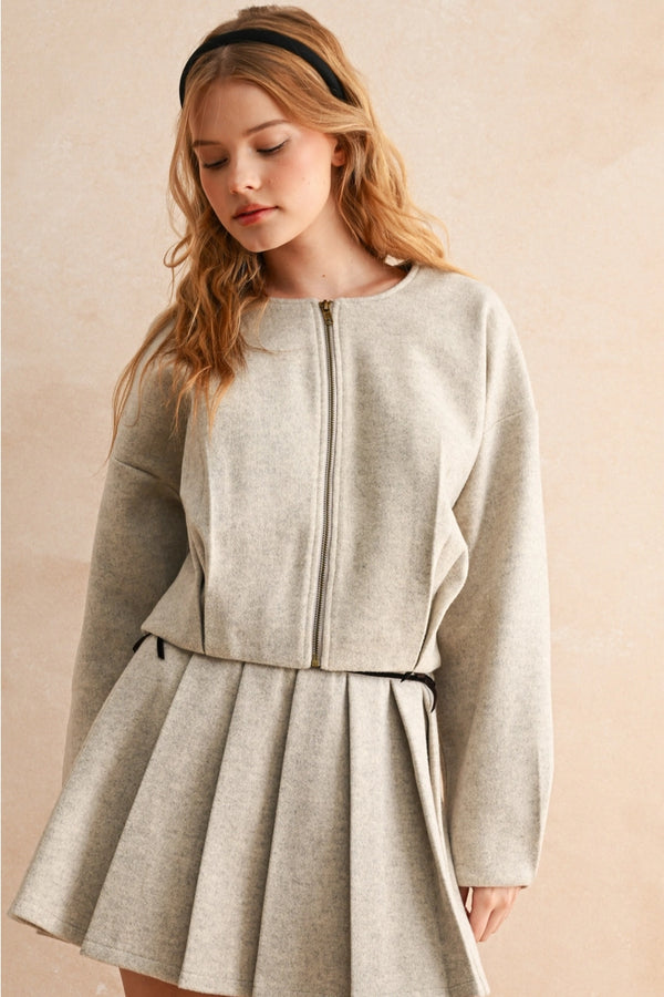 Woman wearing a light gray dress with a zipper on a beige background